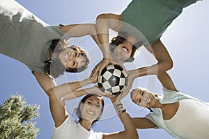 Friends Holding Soccer Ball Together In Huddle photo