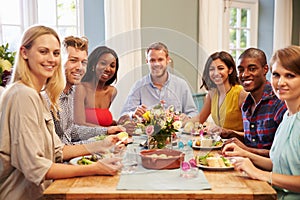 Friends At Home Sitting Around Table For Dinner Party