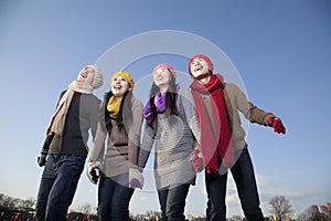 Friends on ice rink, holding hands and smiling