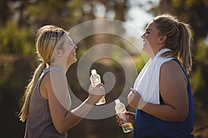 Friends interacting while having water after workout during obstacle course