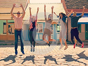 Friends jumping at sunny day on the street