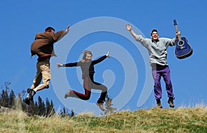 Friends jumps over a grass field on mountain