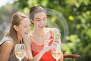 Friends laughing while using mobile phone