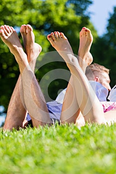 Friends laying with crossed legs in park