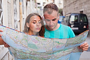 Friends loking on the map on the street. They are on holidays.