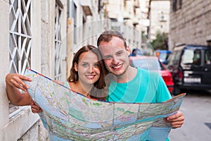 Friends loking on the map on the street. They are on holidays.