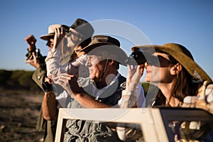 Friends looking through binoculars during safari vacation