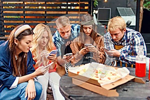 Friends looking at their smartphones at a boring party. Concepts of technology and modern lifestyle problems.