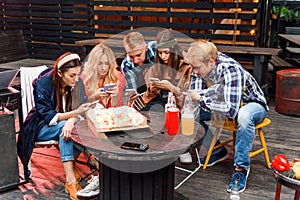 Friends looking at their smartphones at a boring party. Concepts of technology and modern lifestyle problems.