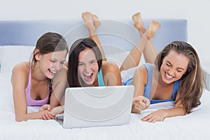 Friends lying on bed with laptop
