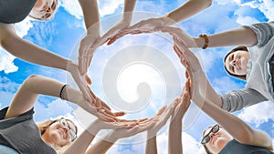 Friends make a circle from their palms against the background of a fabulous sky.