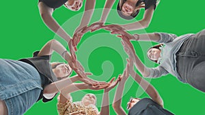 Friends make a circle with their palms against a green background.