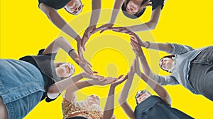 Friends make a circle with their palms against a yellow background.