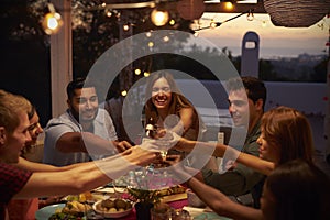 Friends make a toast at a dinner party on a patio, close up