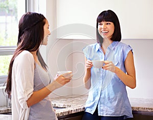 Friends make the world go round. Two women chatting together over coffee in the kitchen.