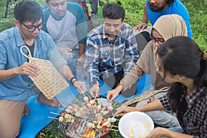 Friends making a barbecue together outdoors