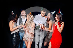 Friends making big party in the night. Six people having fun and drinking champagne on black background