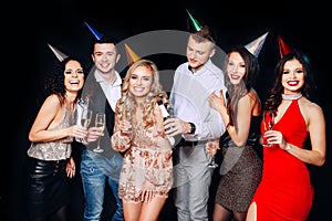 Friends making big party in the night. Six people having fun and drinking champagne on black background