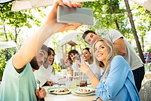 Friends making selfie photo in outdoor restaurant