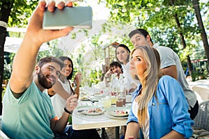 Friends making selfie photo in outdoor restaurant