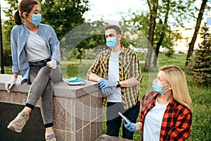 Friends in masks leisures in park, quarantine