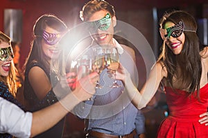 Friends in masquerade masks toasting with champagne