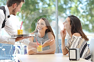 Friends meeting in a bar with a waiter serving photo