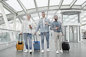 Friends Men Traveling Walking With Suitcases Holding Coffee In Airport