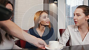 Friends met at the bar. Three young smiling women sitting in a cafe and talking