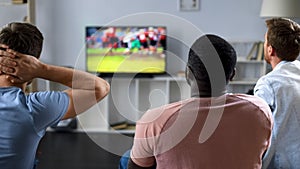 Friends nervously watching american football competition on screen, sofa experts