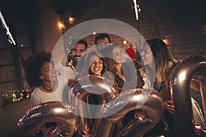 Friends at New Years party, waving with sparklers at midnight countdown