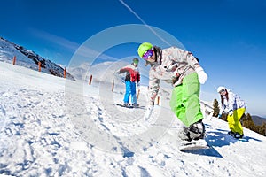 Friends and one man is snowboarding downhill photo