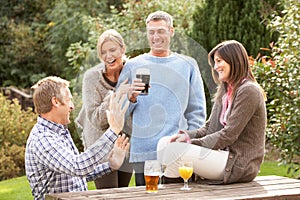 Friends Outdoors Enjoying Drink In Pub Garden