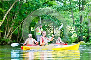 Friends paddling with canoe on forest river