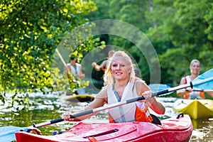 Friends paddling with kayak or canoe on forest river