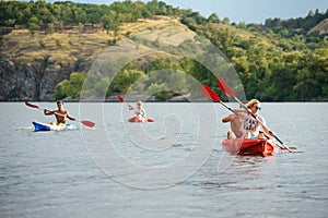 Friends Paddling Kayaks on Beautiful River or Lake at the Evening