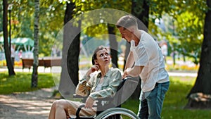 Friends in park - a guy talking with disabled woman in a wheelchair