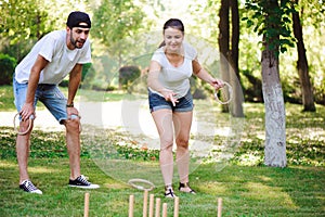 Friends plaing outdoor games - ring toss in summer park.