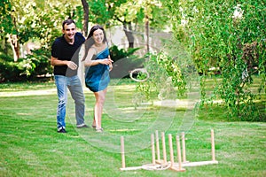 Friends plaing outdoor games - ring toss in summer park.