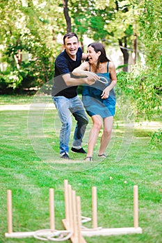 Friends plaing outdoor games - ring toss in summer park.