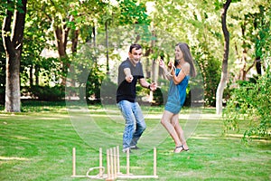 Friends plaing outdoor games - ring toss in summer park.