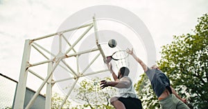 Friends play amateur basketball on the basketball court. A Black person dribbles a black and white ball and perfectly