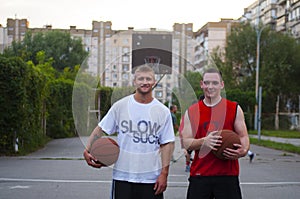 Friends play basketball. Basketball players look at the camera in the ball.