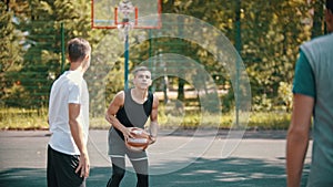 Friends playing basketball on the sports ground - a man aiming in the hoop and throwing the ball