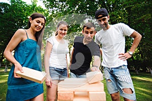 Friends playing board game outdoors. Group game of physical skill with big blocks