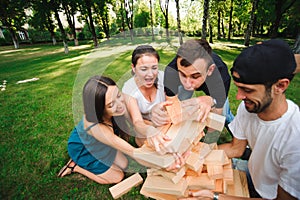 Friends playing board game outdoors. Group game of physical skill with big blocks