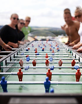 Friends playing with a foosball at a party for competition, fun skill or sports event. Celebration, activity and group