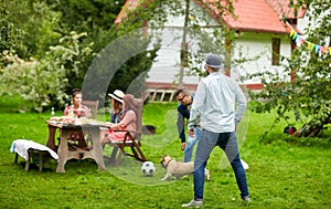 Friends playing football with dog at summer garden