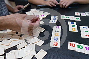 Friends playing to a strategy game board on a table. Blocks of number and statistic for score and win in a tabletop at home. Hands