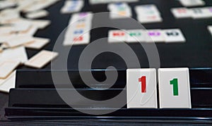 Friends playing to a strategy game board on a table. Blocks of number and statistic for score and win in a tabletop at home. Hands